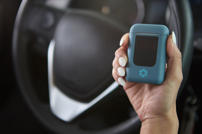 The Keepr personal breathalyzer device being held over the steering w