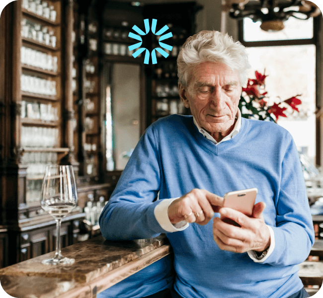 An older gentleman in a bar looking at something on his phone.