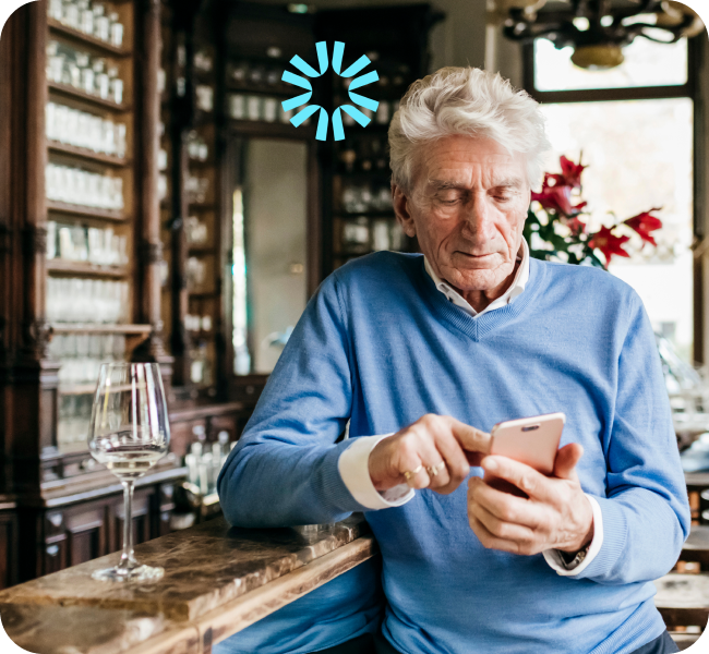 An older gentleman in a bar looking at something on his phone.