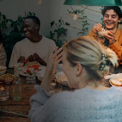 A lively multicultural group of friends sharing a laugh during a backyard dinner party. 