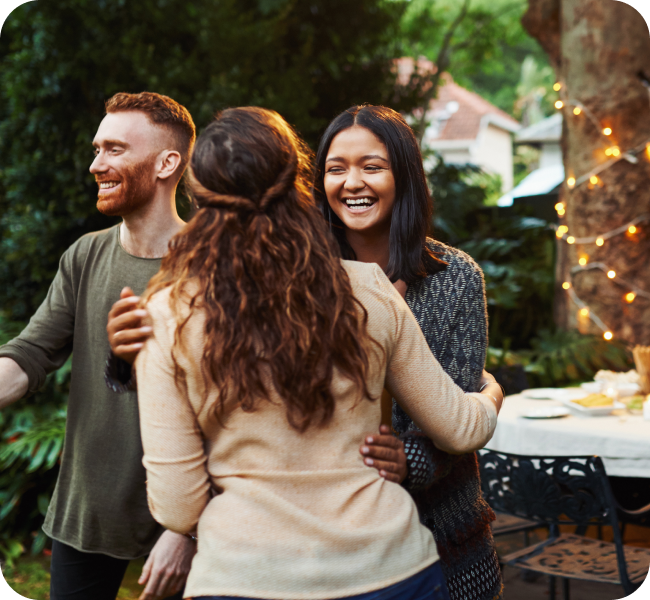 Two friends share a warm embrace at a backyard get together.