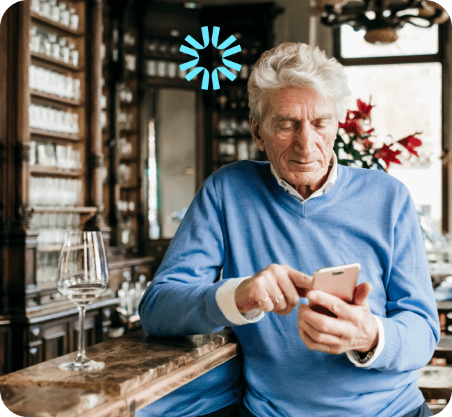 An older gentleman in a bar looking at something on his phone. 