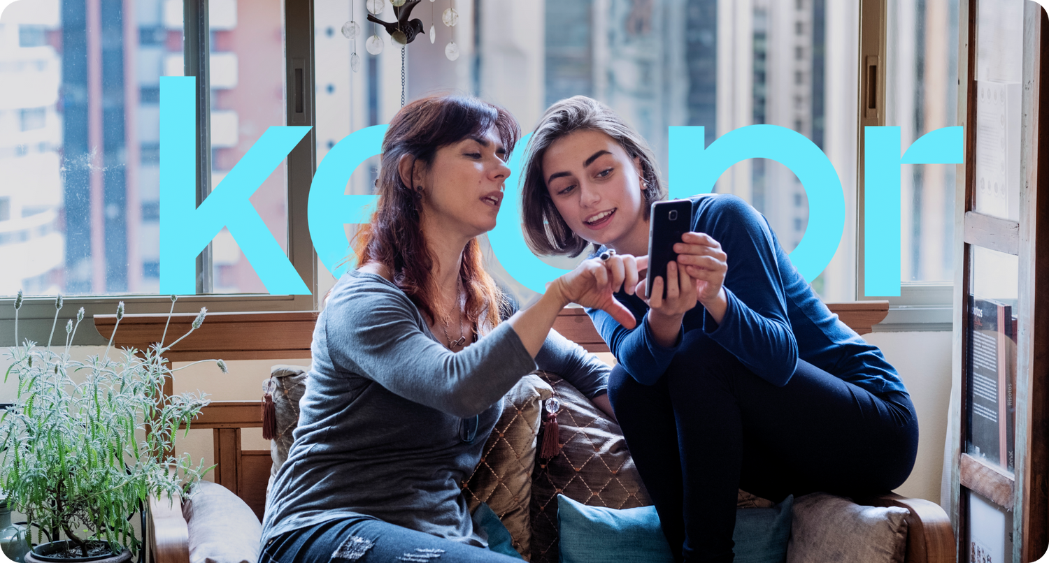 A picture of two women, with one woman pointing something out on her friend’s phone.