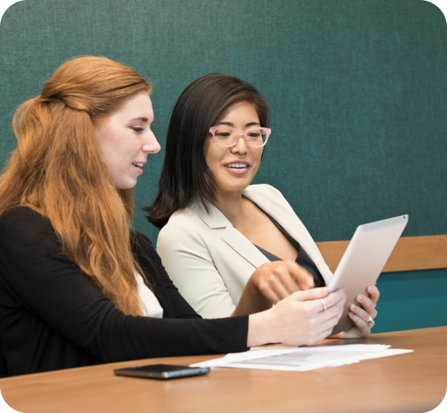 two professionally dressed young females reviewing their notes